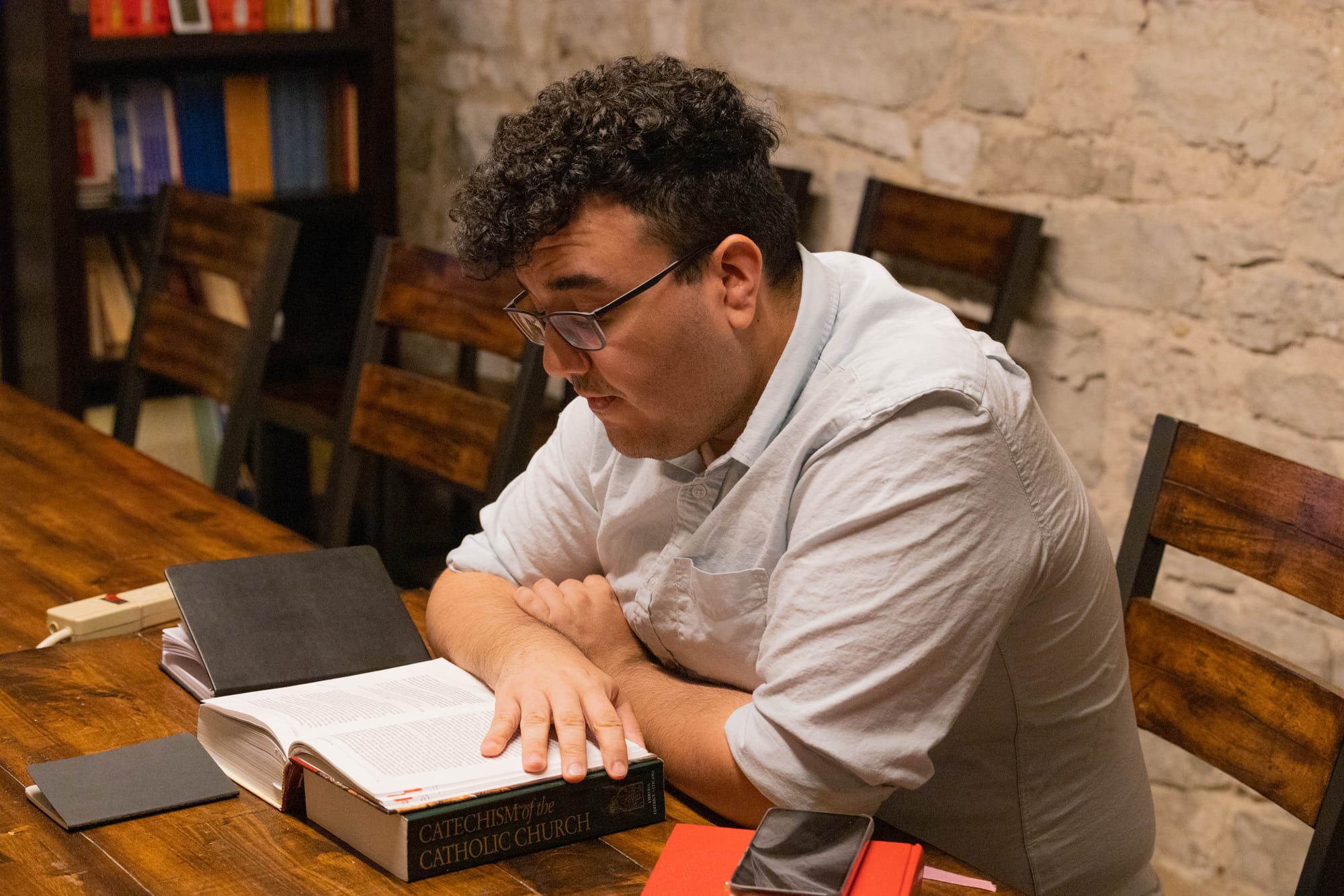 Capuchin Postulant Scott Cotto seated at a table, reads from a book.