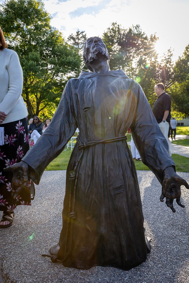 A bronze statue of St. Francis kneeling as he receives the Sacred Stigmata.