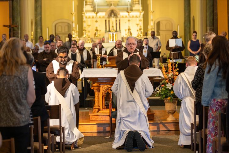 Capuchin Franciscan priests lay hands on friars Truong Dinh, Francisco Javier Rodriguez and Nathan Linton during ordination.